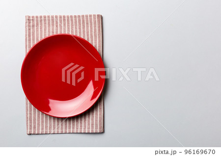 Top view on colored background empty round red plate on tablecloth for food. Empty dish on napkin with space for your design Top view on colored background empty round red plate on tablecloth for food. Empty dish on napkin with space for your design 96169670