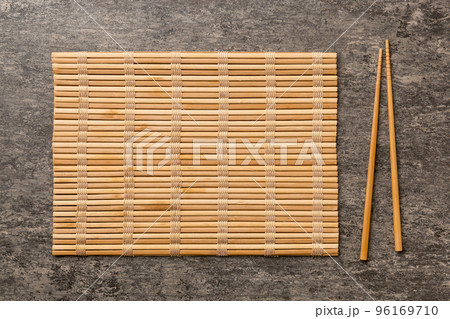 Two chopsticks and bamboo mat on cement background. Top view, copy space Two chopsticks and bamboo mat on cement background. Top view, copy space 96169710