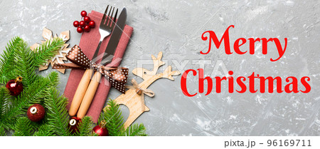 Merry Christmas text. Top view of flatware tied up with ribbon on napkin on cement background. Banner Christmas decorations and reindeer with empty space for your design. New Year holiday concept 96169711