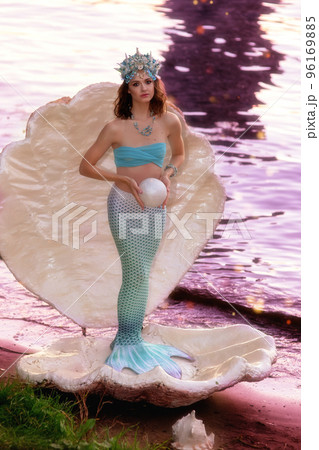 A beautiful mermaid girl stands in a large white shell 96169885