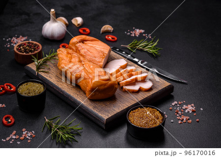 Tasty smoked fillet of chicken breast with spices and herbs on a wooden cutting board 96170016