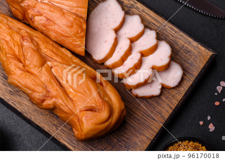 Tasty smoked fillet of chicken breast with spices and herbs on a wooden cutting board 96170018