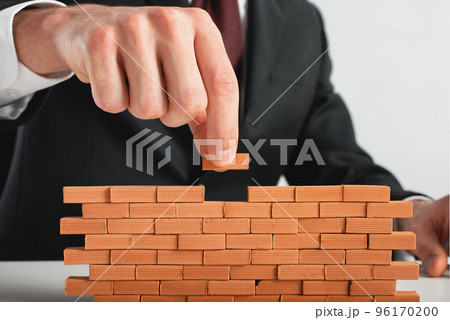 Businessman puts a brick to build a wall. Concept of new business, partnership, integration and startup. 96170200