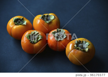 Orange persimmon fruits on a black background. Ripe and juicy persimmon fruits close-up. 96170377