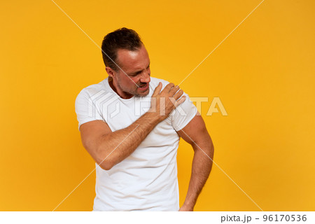 Aching man with back pain. Yellow background Aching man with back pain. Yellow background 96170536