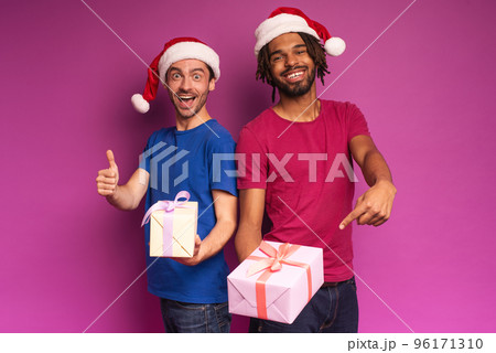 Amazed friends happy by the arrival of Christmas with present. Purple background 96171310