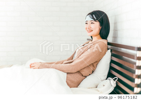 ベッドで休む冷却シートをつけた笑顔のアジア人女性 ベッドで休む冷却シートをつけた笑顔のアジア人女性 96175182