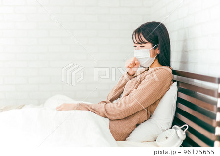 風邪をひいてベッドで咳をする体調不良のマスクをしたアジア人女性 96175655