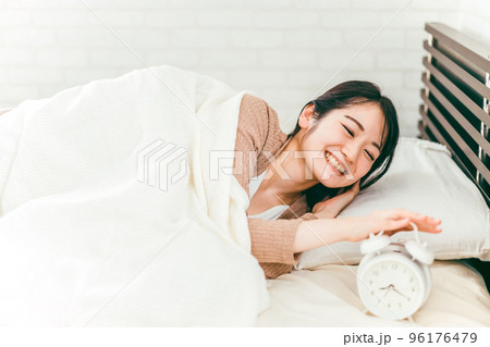 朝ベッドルームでスッキリと笑顔で起床する日本人女性 96176479
