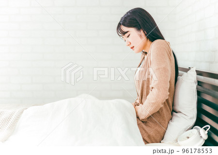 ベッドルームで腹痛・生理痛に悩む日本人女性 96178553