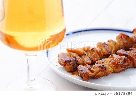 炭火焼にしたタレの焼き鳥（とり皮）をつまみにビールを飲む 96178894