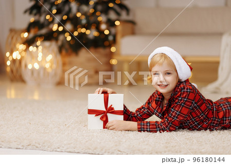 The girl lies on the floor with a gift in a box The girl lies on the floor with a gift in a box 96180144