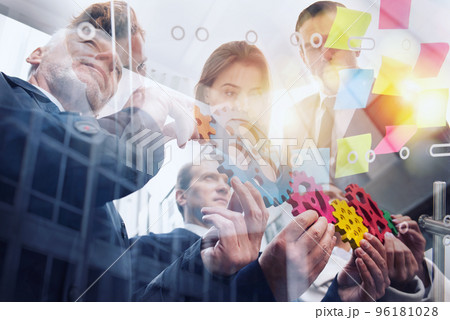 Business team connect pieces of gears. Teamwork, partnership and integration concept. Double exposure Business team connect pieces of gears. Teamwork, partnership and integration concept. Double exposure 96181028