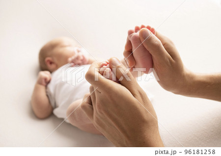 Mother is doing massage on her baby foot. Close up baby feet in mother hands on a white background. Prevention of flat feet, development, muscle tone, dysplasia. Family, love, care, and health concept Mother is doing massage on her baby foot. Close up baby feet in mother hands on a white background. Prevention of flat feet, development, muscle tone, dysplasia. Family, love, care, and health concept 96181258