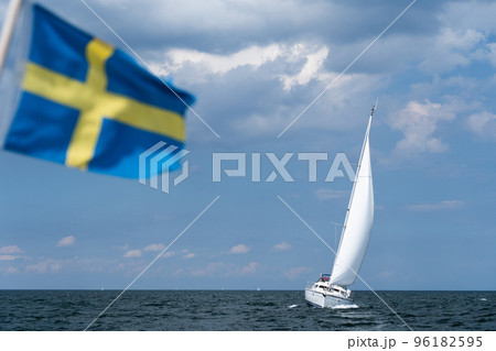 Sailboat on blue open sea with Sweden flag foreground. Concept of travel, adventure and vacation. Sailboat on blue open sea with Sweden flag foreground. Concept of travel, adventure and vacation. 96182595