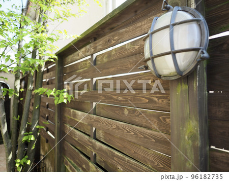 南欧風アーチ扉のある中庭　ウッドフェンスにテラコッタの床のパティオ　ヤマボウシの木と新緑の 96182735