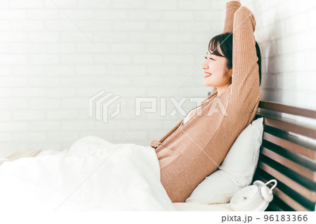 朝ベッドルームで熟睡・快眠できて笑顔でストレッチする女性 96183366