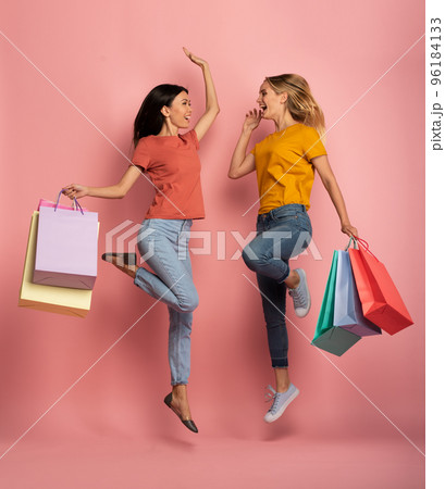 Two girls are happy after shopping. Joyful expression. Shop concept. Pink background 96184133