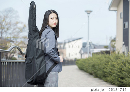 ギターを背負って学校へ行くスタックスを履いた女子高生 96184715