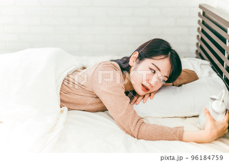 寝坊して目覚まし時計で起きる女性（遅刻） 96184759