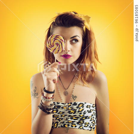 Young woman eating lollipop in yellow style 96185085