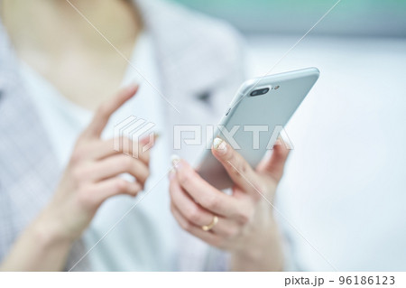 スマートフォンを操作する女性の手元 96186123