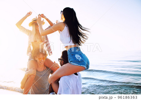 Happy smiling couples playing at the beach 96186363
