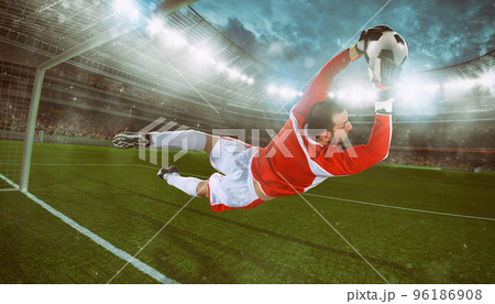 Goalkeeper catches the ball in the stadium during a football game Goalkeeper catches the ball in the stadium during a football game 96186908