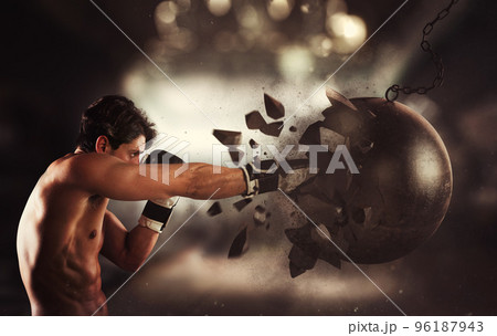 Power and determination of a young muscular boxer against a wrecking ball 96187943