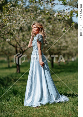 Portrait of a blonde in the park. Beautiful woman with long blond hair in a blue dress. 96188288