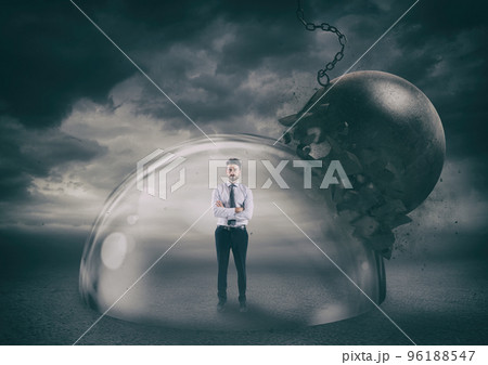 Businessman safely inside a shield dome during a storm that protects him from a wrecking ball. Protection and safety concept Businessman safely inside a shield dome during a storm that protects him from a wrecking ball. Protection and safety concept 96188547
