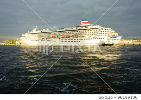 Sun rays break through storm clouds in the evening sky. Cruise ship Asuka II at sunset. Dark sea water Sun rays break through storm clouds in the evening sky. Cruise ship Asuka II at sunset. Dark sea water 96189106