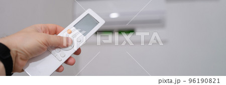 Person manual air conditioner with remote control closeup Person manual air conditioner with remote control closeup 96190821