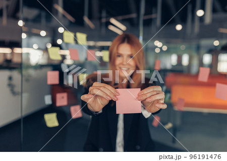 Businesswoman showing empty sticky notes while standing in modern office 96191476