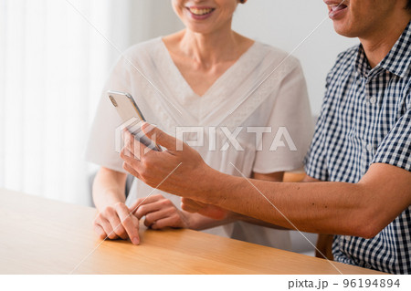 スマートフォンを一緒に見るミドル男性とミドル女性 スマートフォンを一緒に見るミドル男性とミドル女性 96194894