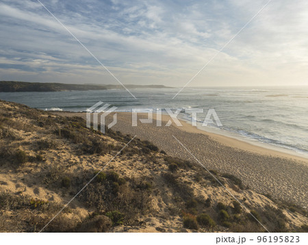 View of empty sand beach Praia do Farol at Vila Nova de Milfontes with view of ocean waves. Golden hour light View of empty sand beach Praia do Farol at Vila Nova de Milfontes with view of ocean waves. Golden hour light 96195823