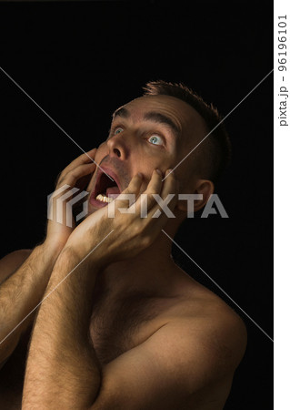Shirtless man with frightened expression on black background. Portrait of a man with his hands on his face and mouth open. Shock at what he saw. Shirtless man with frightened expression on black background. Portrait of a man with his hands on his face and mouth open. Shock at what he saw. 96196101