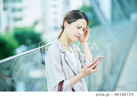 困った表情でスマートフォンの画面を見る若い女性 困った表情でスマートフォンの画面を見る若い女性 96196729