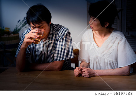 家でうなだれるミドル男性と彼を慰めるミドル女性 96197538