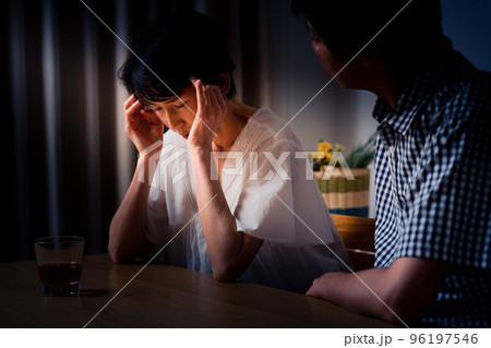 家でうなだれるミドル女性と彼を慰めるミドル男性 96197546