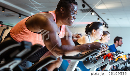 African man and friends on fitness bike in gym African man and friends on fitness bike in gym 96199536