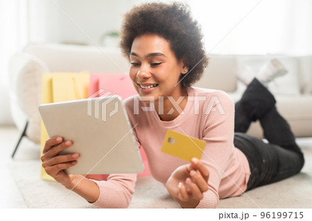 Happy millennial african american lady with many packages with purchases shows credit card 96199715