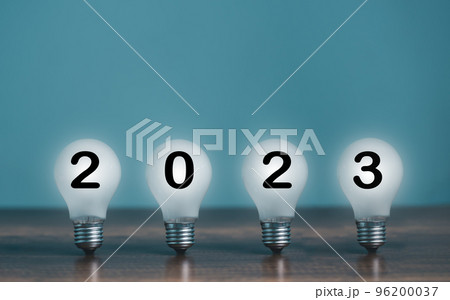 Turn On shine bright light bulb with 2023 Happy New Year on the desk and copy space for text decoration. 96200037