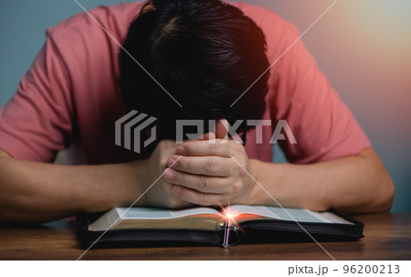 People holding hands head bow down pray to God in the middle book holy bible book with cross necklace front of the holy bible.. 96200213