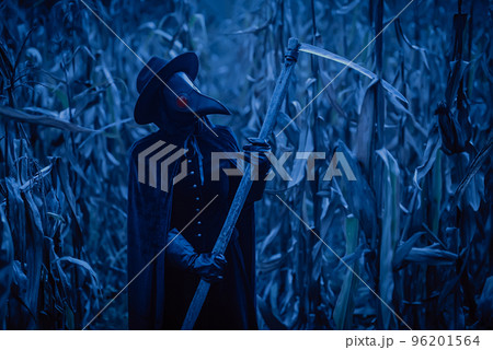 Plague doctor gothic woman with sharp scythe at night in thickets of corn field. Creepy raven mask Plague doctor gothic woman with sharp scythe at night in thickets of corn field. Creepy raven mask 96201564