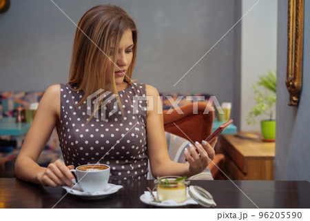 Beautiful thoughtful woman using a mobile phone in cafe. Reading news or SMS 96205590