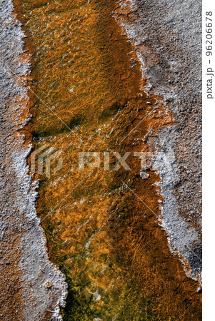 High angle close-up of hot stream flowing on geothermal landscape. Textured yellow surface in geyser basin. Famous tourist attraction at Yellowstone National Park. High angle close-up of hot stream flowing on geothermal landscape. Textured yellow surface in geyser basin. Famous tourist attraction at Yellowstone National Park. 96206678