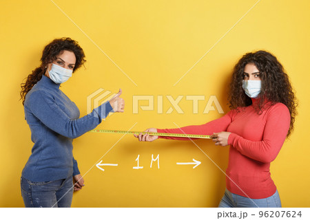 Friends keep distance between them of 1 meter. Concept of codiv-19 rules to avoid pandemic. yellow background. 96207624