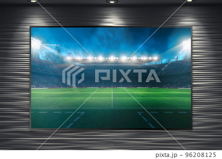 Watching a soccer event on a large TV wall mounted and illuminated by spotlights 96208125