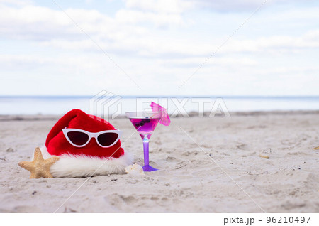 Santa Claus hat with sunglasses on the beach with cocktail and starfish Santa Claus hat with sunglasses on the beach with cocktail and starfish 96210497